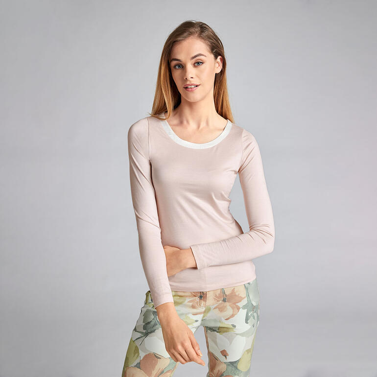 rosé Vrouw in lichtroze zijden top met lange mouwen en ronde halslijn.