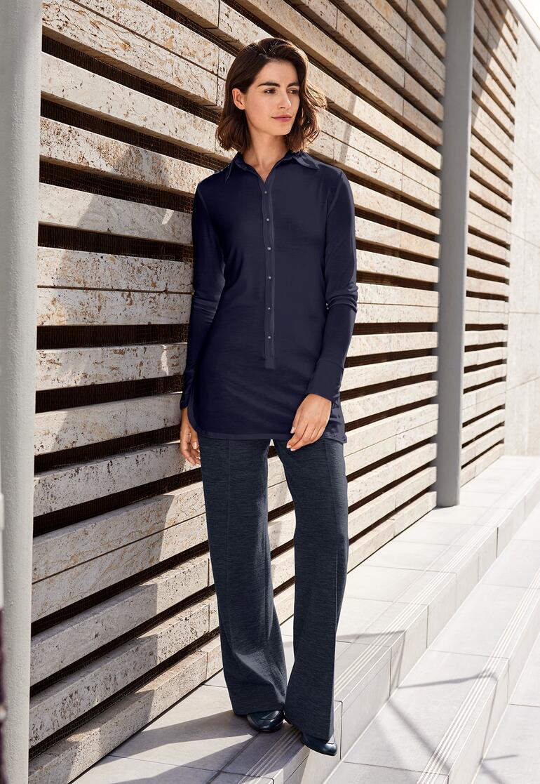 marine Lange Tencel-blouse in donkerblauw, leunend tegen een muur buiten.