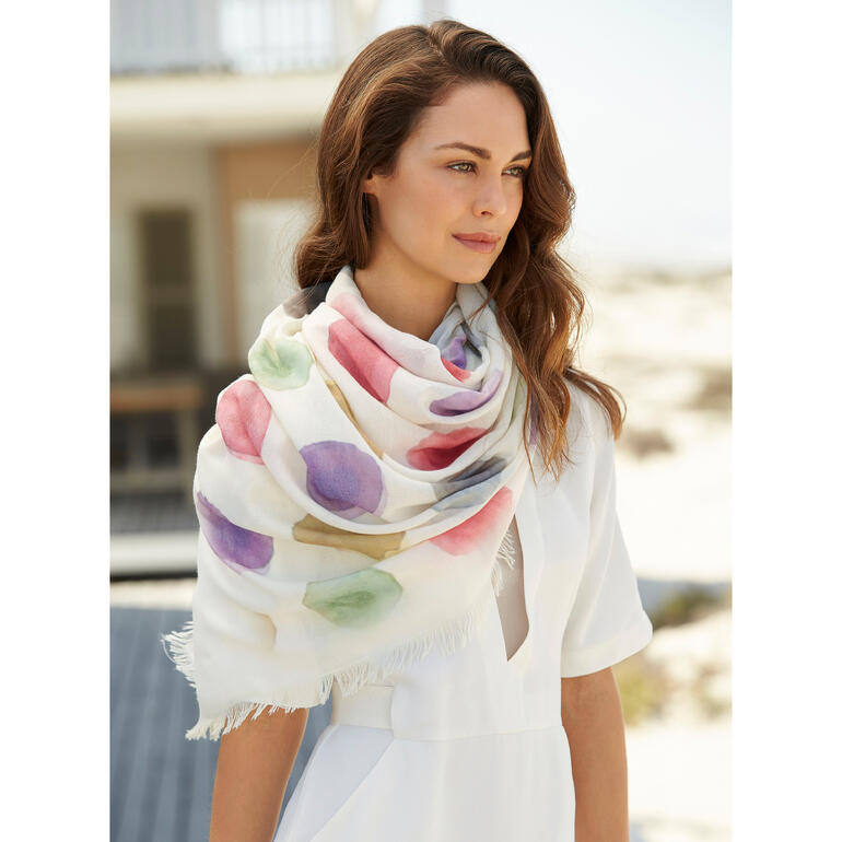 Vrouw draagt een kleurrijke schouderlange Dotted-sjaal met aquarelpuntjes.