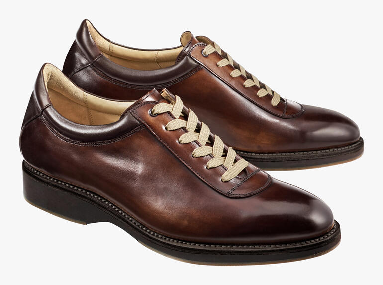 Twee Cordwainer Edelsneakers in bruin op een lichte achtergrond.
