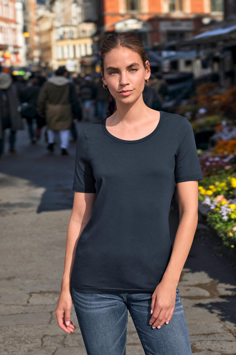Vrouw in een marineblauw T-shirt met korte mouwen op een straat in de stad.