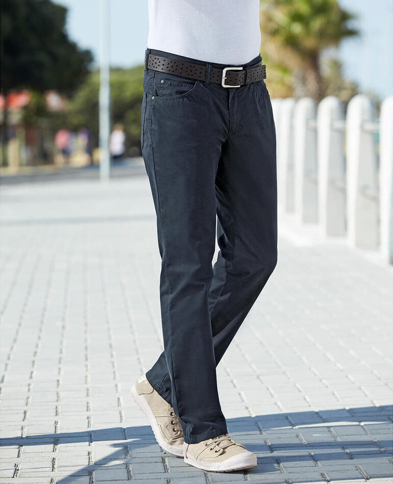 Coolmax® zomerse five-pocketsbroek Man loopt op een trottoir in Coolmax® zomer Five-Pocket-broeken.