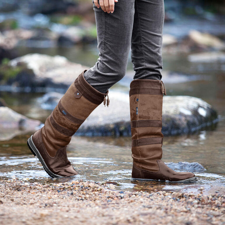 Dubarry waterdichte leren laarzen Vrouw draagt Dubarry waterdichte leren laarzen in het water in de natuur.