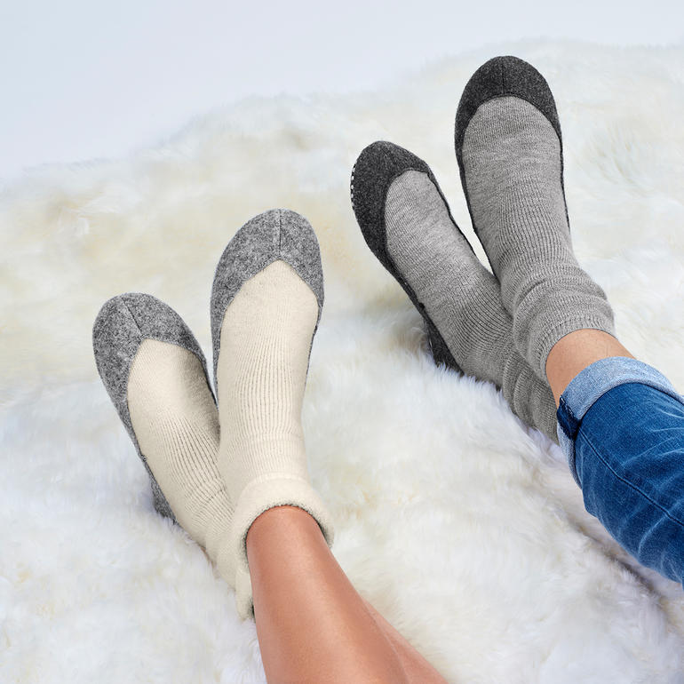 Voeten in huisschoenen met grijze en beige kleur.