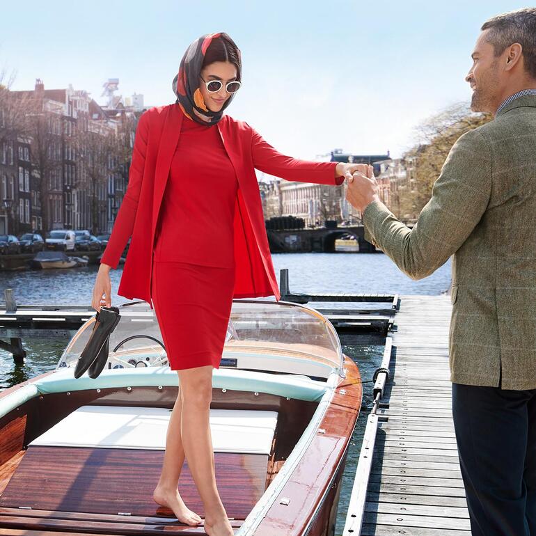 Vrouw in rode outfit, verlaat een boot aan de kade.