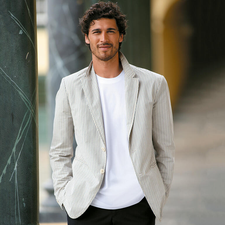 Man draagt een wit Ragman t-shirt onder een gestreepte blazer.