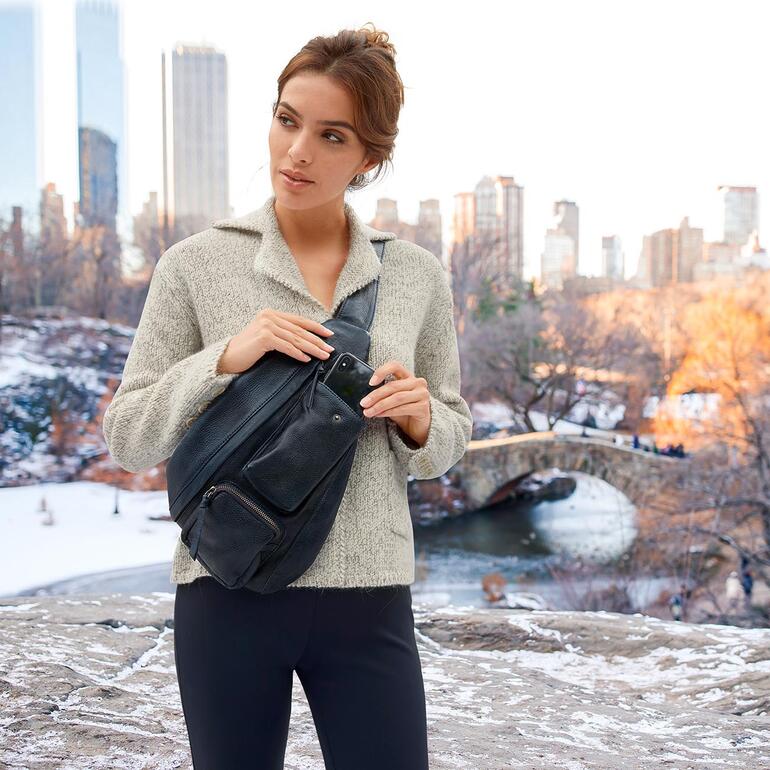 Vrouw met Anokhi Crossbody-Bag in winterse omgeving met een brug op de achtergrond.