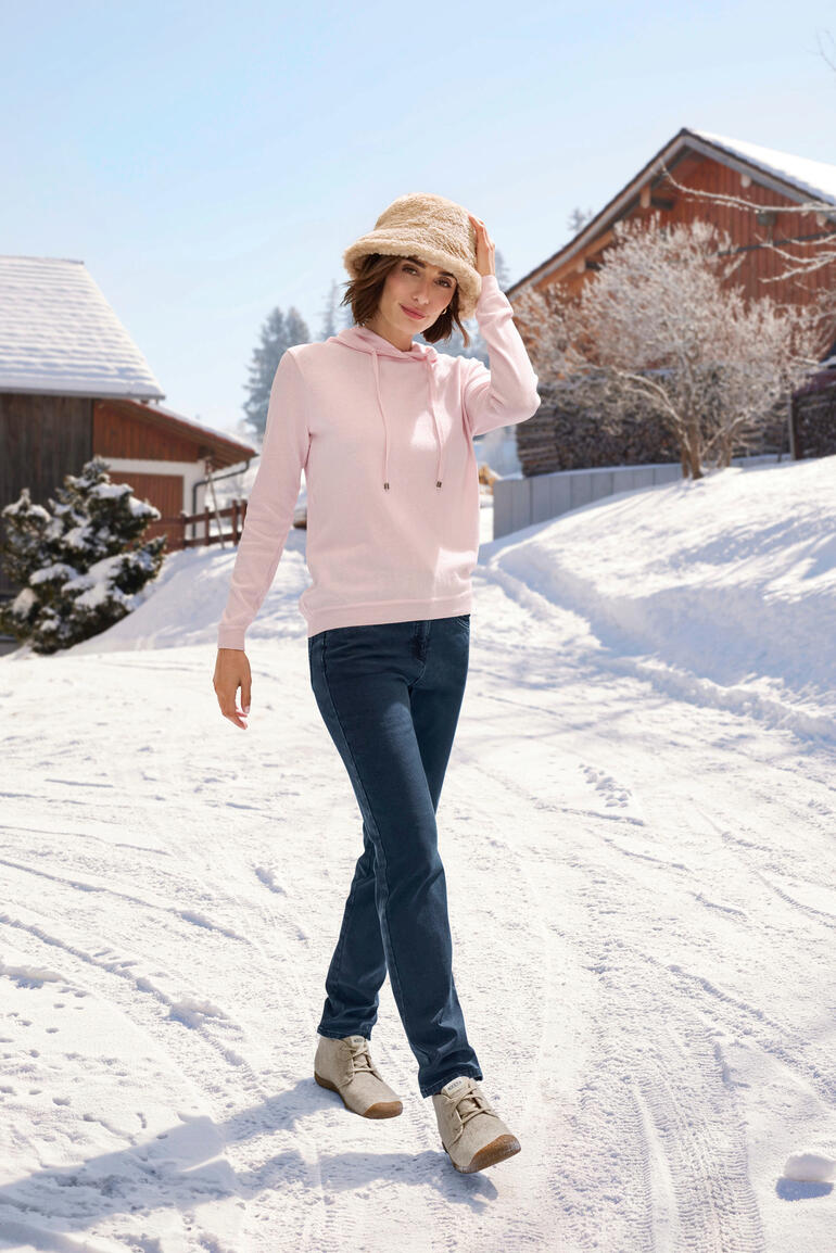 Teddy bucket hat Vrouw in een roze katoen-kashmir hoodie in de sneeuw.