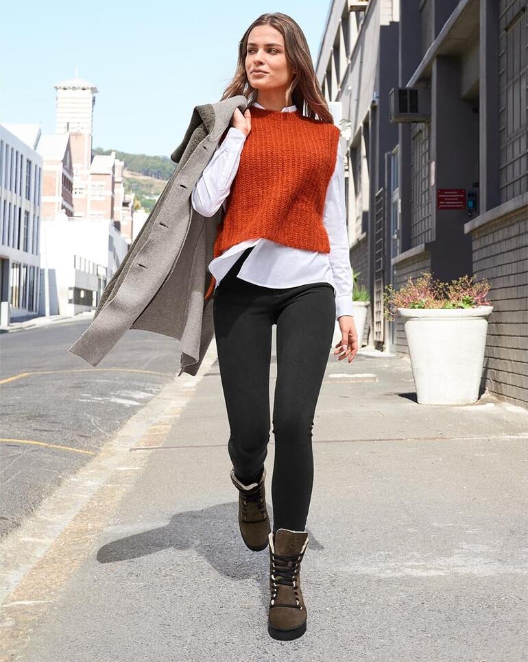 Chaaya boots met lamsvacht en vetersluiting Vrouw in een oranje pullover en grijze jas loopt op het trottoir met laarzen.