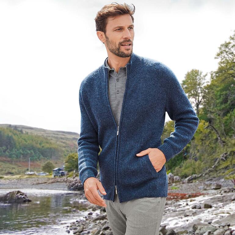 Man in gebreide vest kijkt naar het landschap