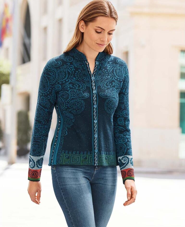 Vrouw draagt een blauwe jacquardjack met paisleymotief buiten op een Europese straat.