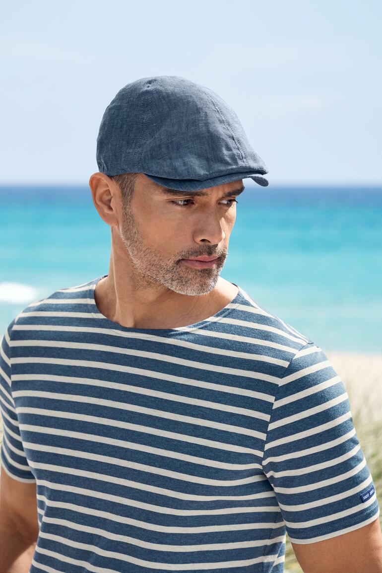 Portret van een man met linnen plat cap aan het strand