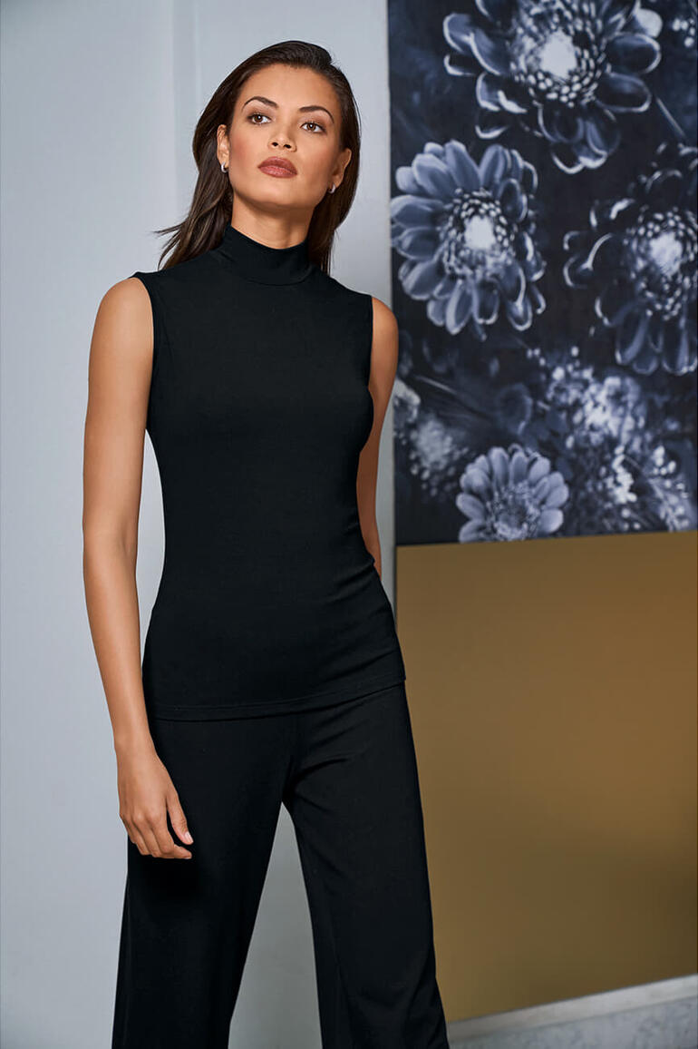 Vrouw in een zwart mouwloos top met hoge kraag voor een bloemgrafiek.