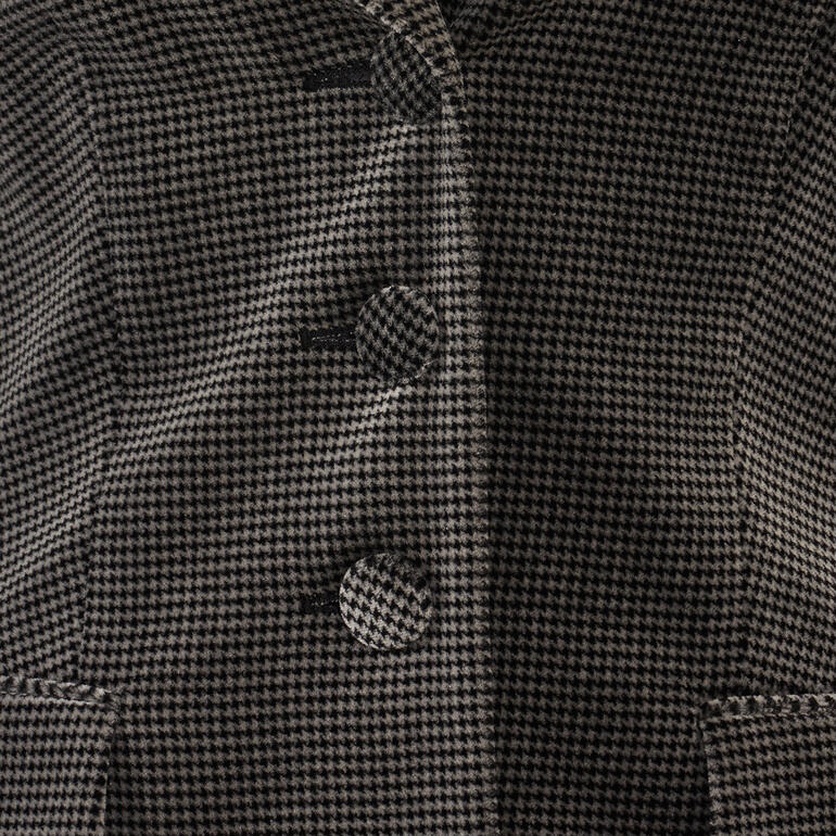 Close-up van de knopen van de wasbare fluwelen blazer in houndstooth.