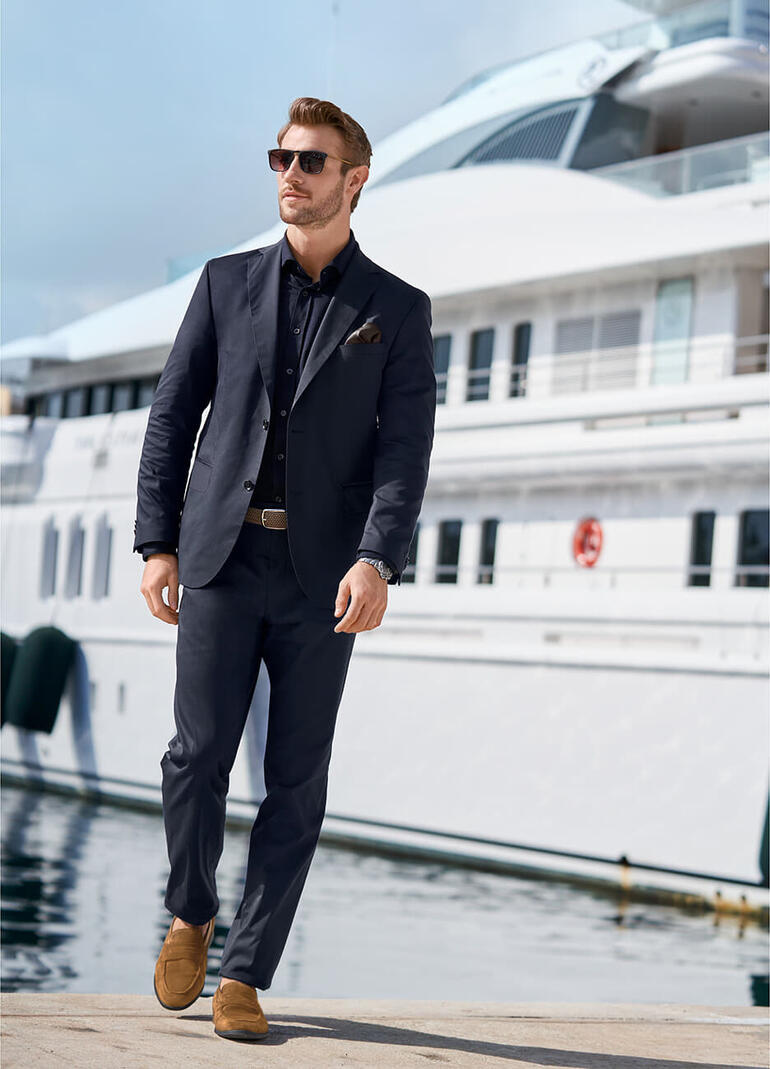 colbert en broek, blauw Man in een donker pak voor een luxe boot.