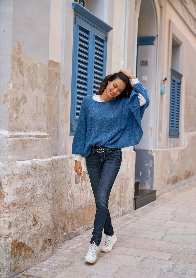 blauw Vrouw draagt een blauwe bouclé poncho trui in een oude stad straat