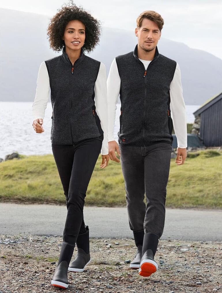 Ivanhoe of Sweden bodywarmer van walk-Tencel™ Stel loopt langs het water, beiden dragen Tretorn neopreen rubber laarzen.