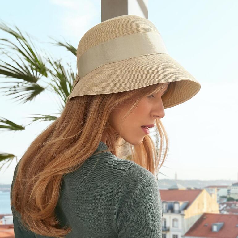 Vrouw draagt een beige borten-zomerhoed in een stedelijke omgeving