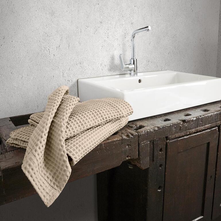 Beige wafelpiqué handdoeken over een houten oppervlak.
