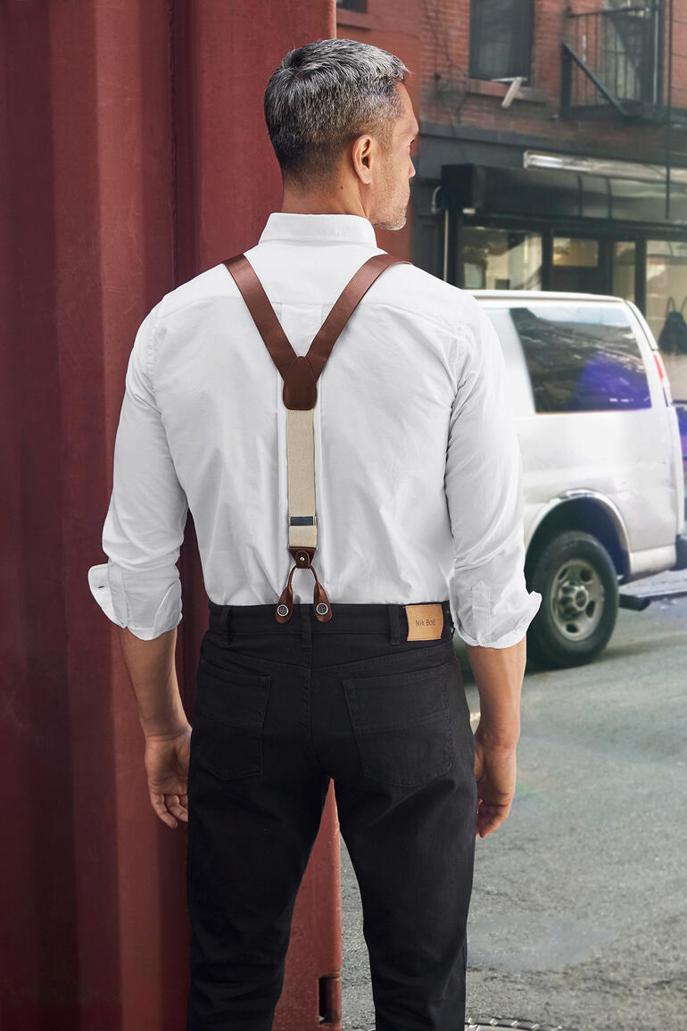 Man met leren bretels en wit hemd van achteren in de stad.