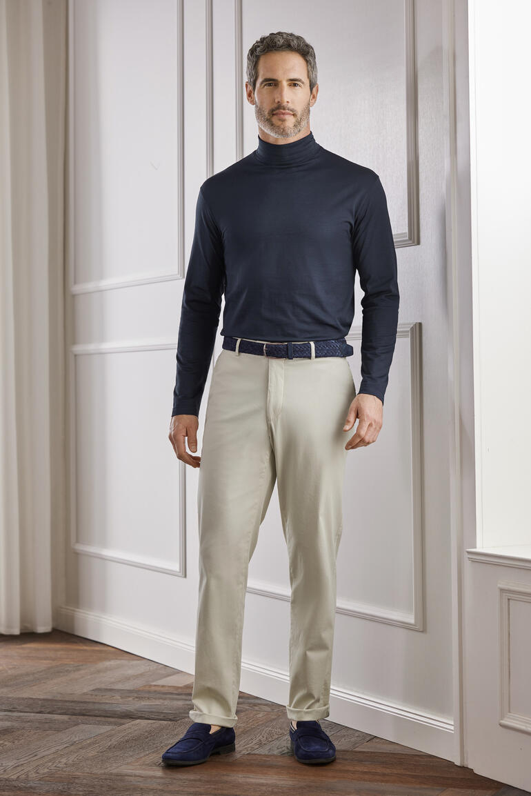 Sunspel colshirt Man in donkere Sunspel ondertrui met lichte broek in een elegante ruimte.