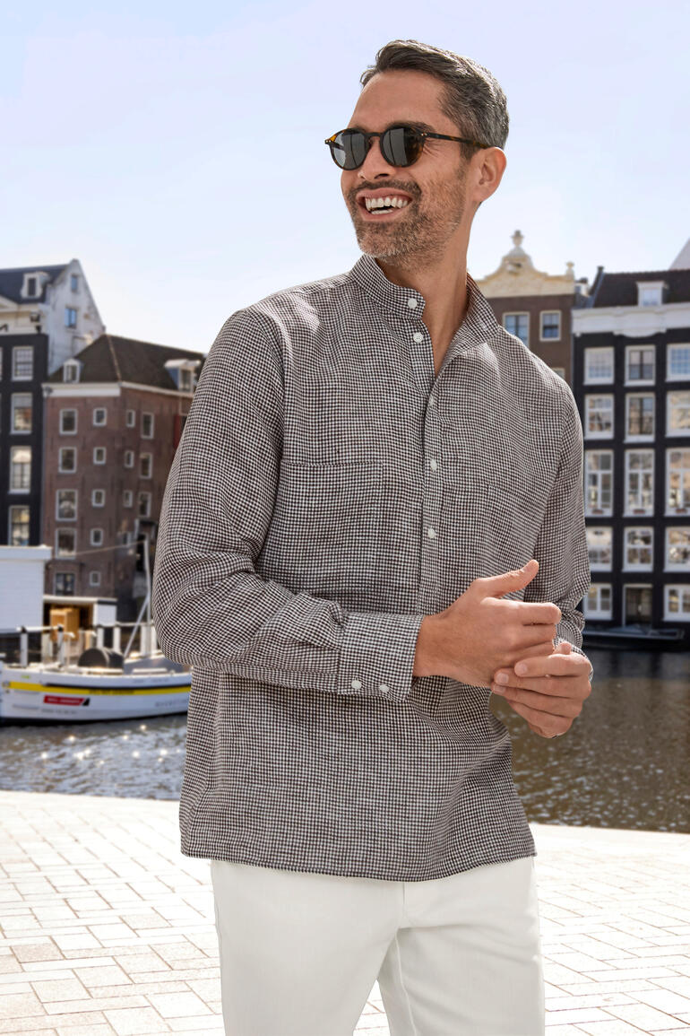 Lachende man in geruite Nehru linnen hemd voor het water in de stad.