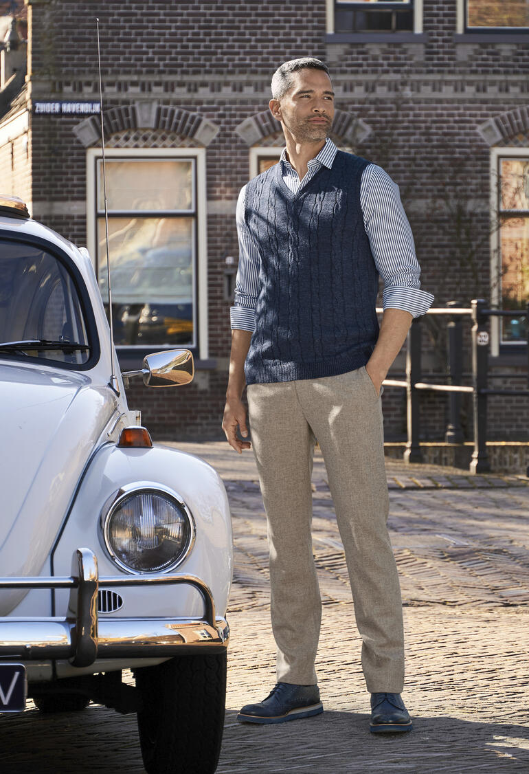blauw Man in lichtgrijze fine loden broek voor een historische auto.