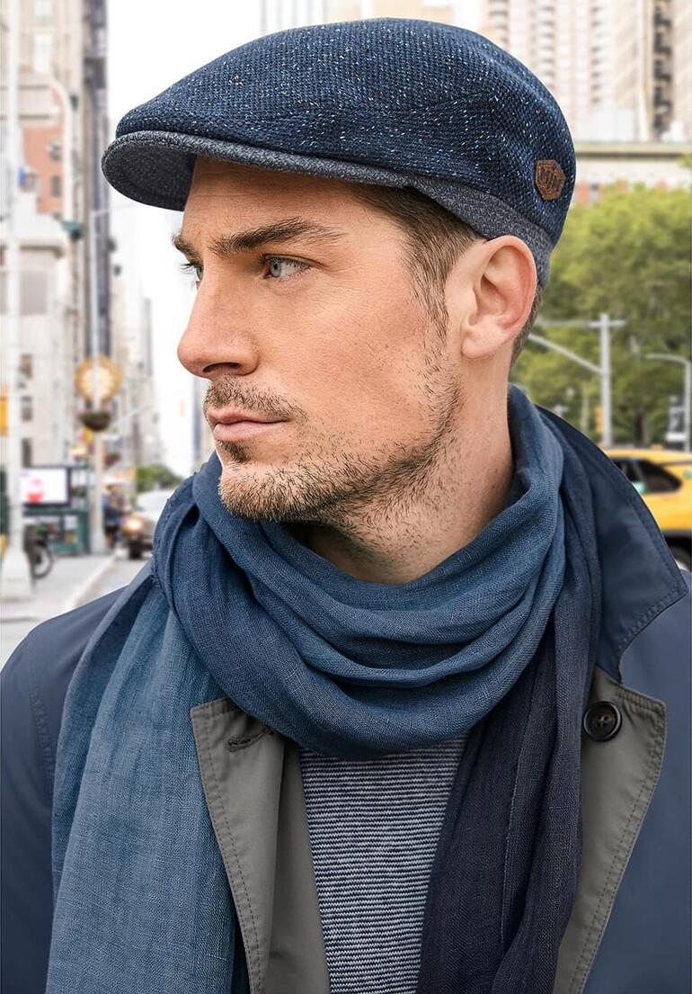 Man met een wol-zijde pet op straat.