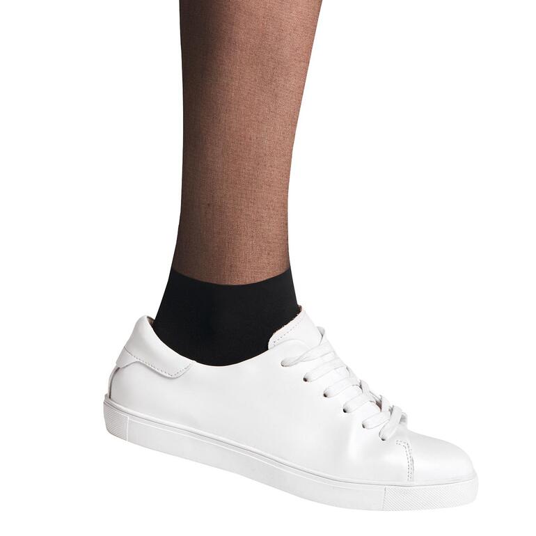 Falke sneaker panty’s Close-up van een voet in een witte sneaker en zwarte Falke sneaker-kousenbroek.