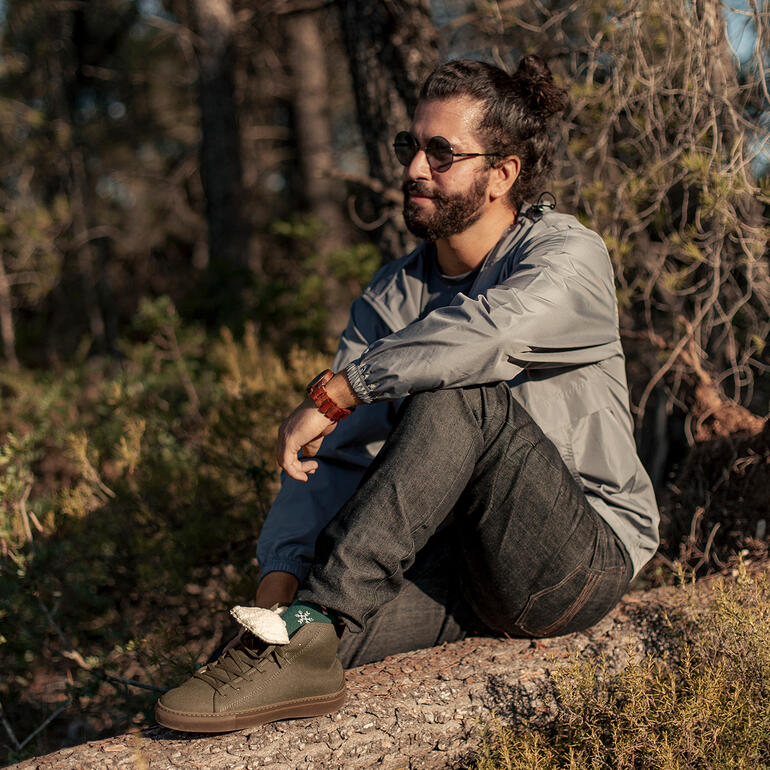 khaki Winter-canvas sneakers aan een man die op een boomstam zit