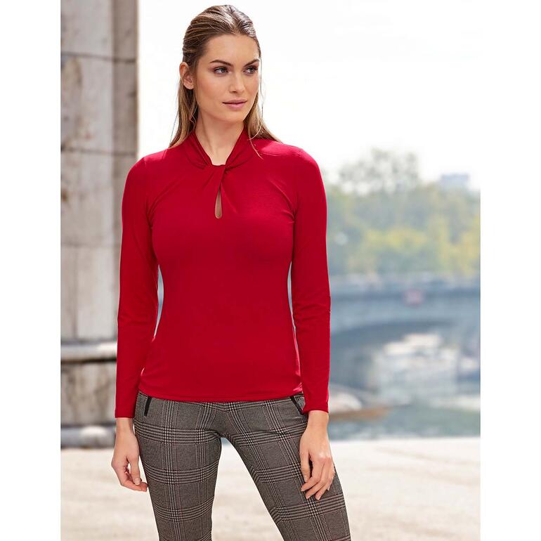 rood Vrouw in een rode Tencel-shirt met een sleutelgat vóór een stedelijke achtergrond.