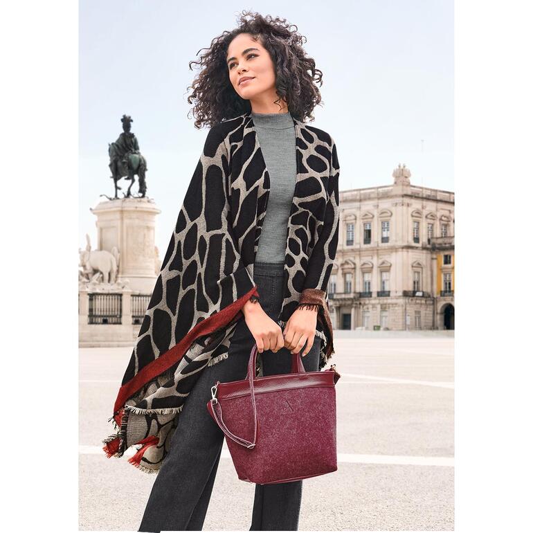 Ancini omkeerbare poncho in verschillende patronen, gedragen door een vrouw in de stad.