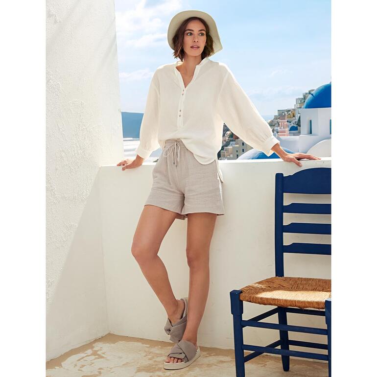 tuniek en short Vrouw draagt offwhite tetra tuniek en shorts op een terras.