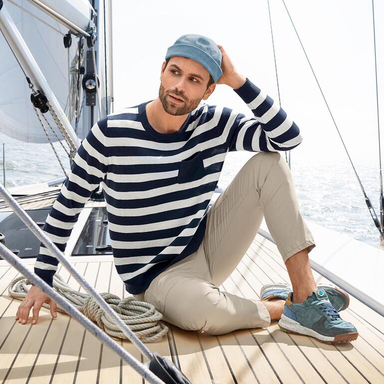 Man in gestreepte trui en Zero-Gravity cargo broek op een zeilboot.