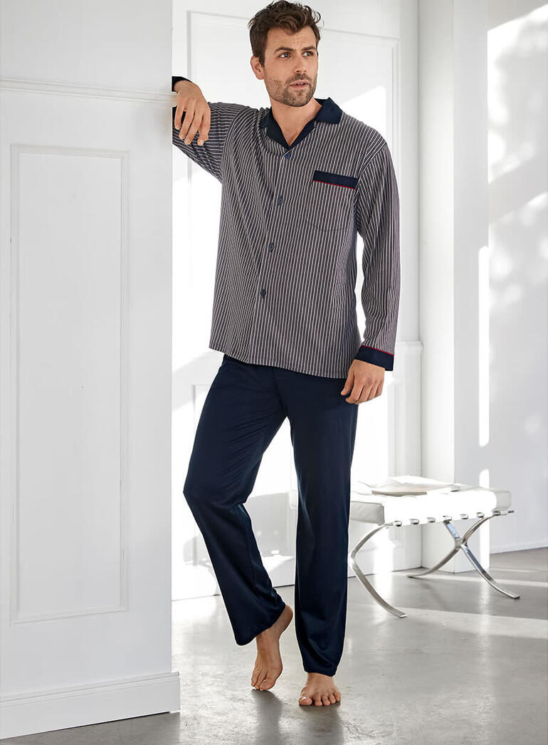 Gentleman-pyjama van interlock Man in gestreepte pyjama staat tegen een muur.