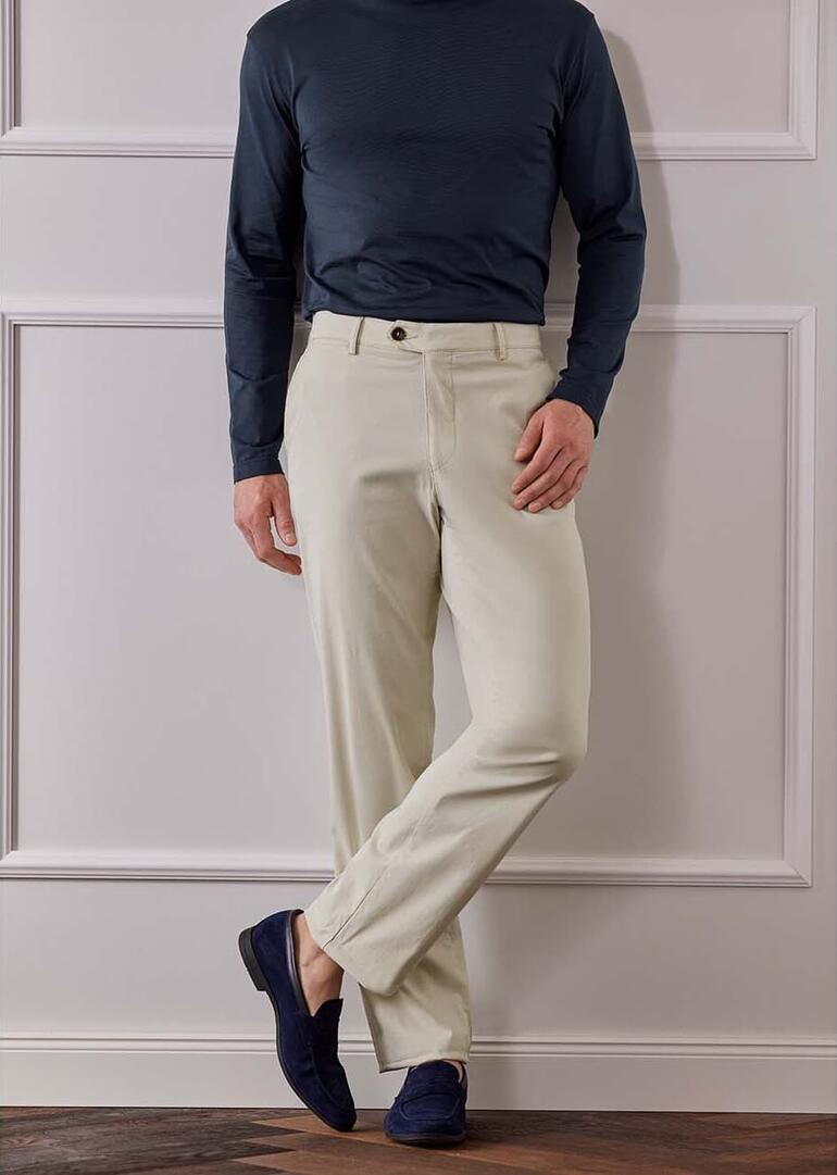 Man in lichte reisbroeken staat op een houten leuning.