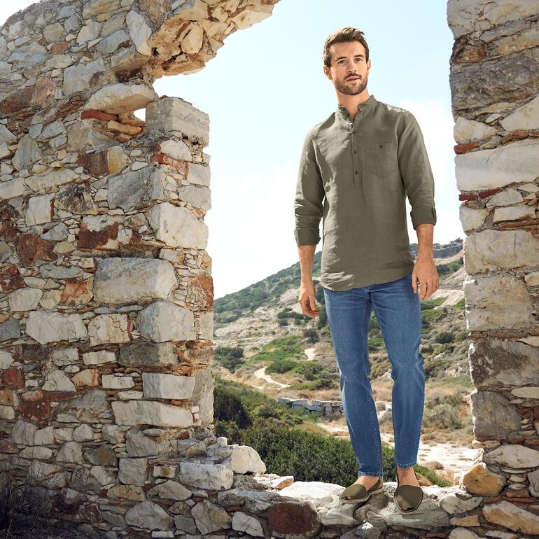khaki Man draagt Eco Avarcas de Menorca voor historische muren in een zonnige omgeving.