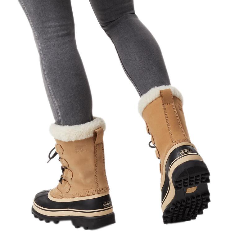 Vrouw draagt Sorel Winterboots 'Caribou' in camel met zwarte onderkant.