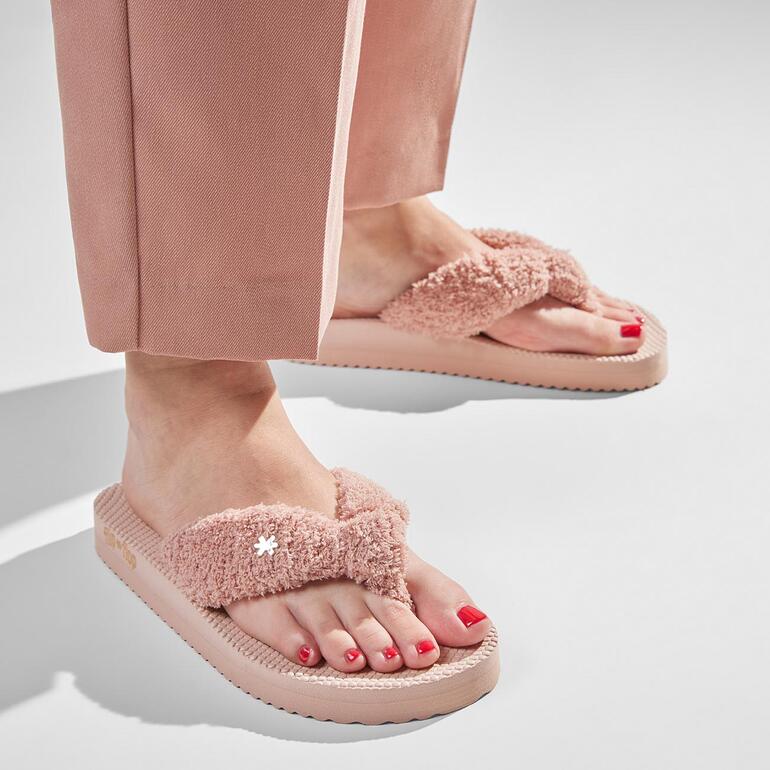 Vrouw draagt roze frottee-flipflops met rode nagellak.