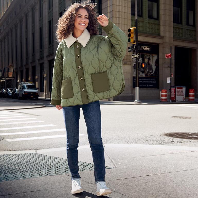 Vrouw draagt vintage sneakers met lichte jas op de straat.