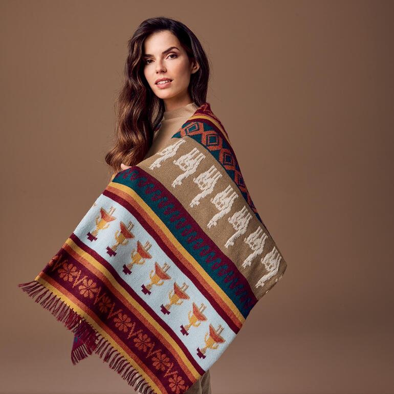 Vrouw draagt een handgebreide alpakashawl met kleurrijk patroon.