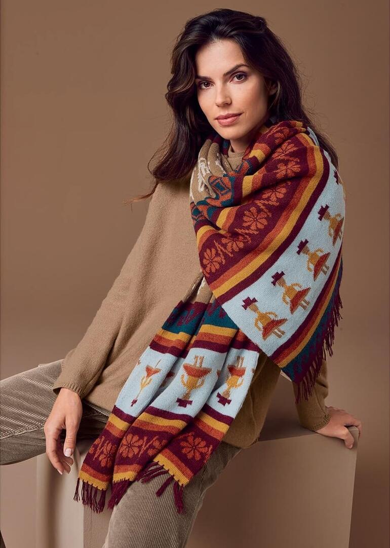 Vrouw met handgebreide alpakashawl kijkt in de camera.