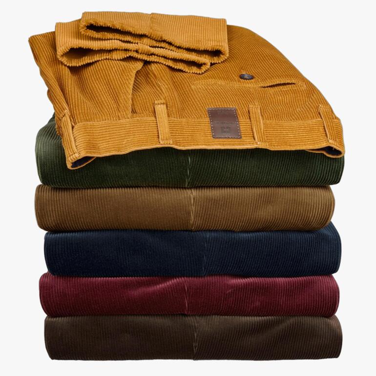 Gestapelde Kindermann corduroy broeken in verschillende kleuren, netjes opgestapeld.