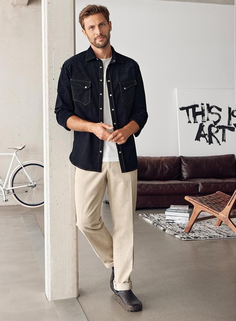 Man in een zwart fluwelen westernshirt met lichte achtergrond