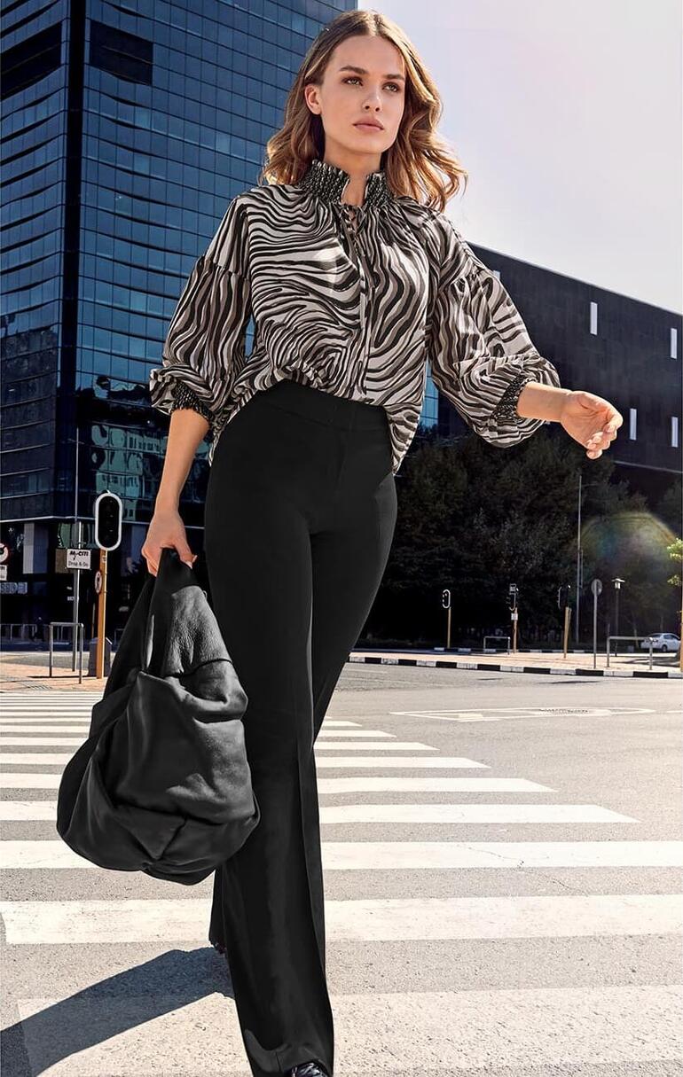 Vrouw in gestreepte blouse loopt op een straat in een stedelijke omgeving.