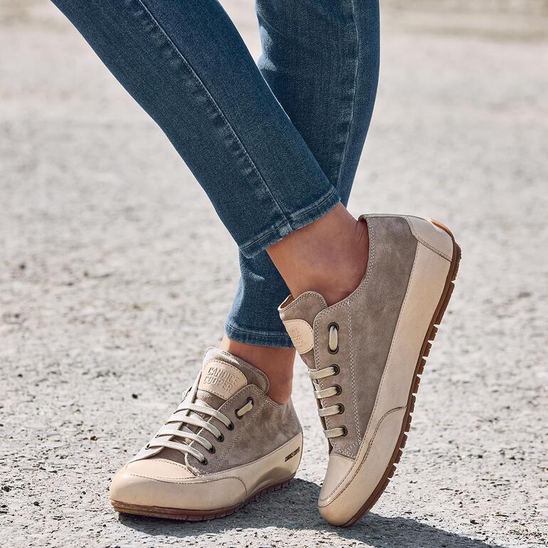 Vrouw in Candice Cooper luxe sneakers die over grind loopt.