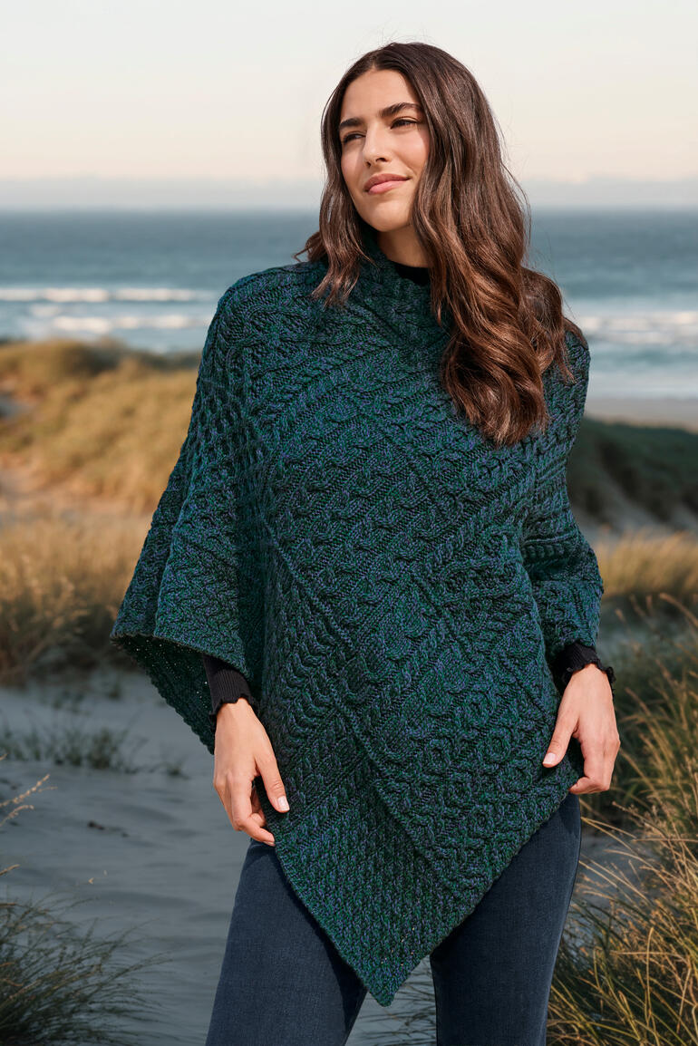 atlantisch blauw Vrouw in een Aran poncho poseert op het strand.