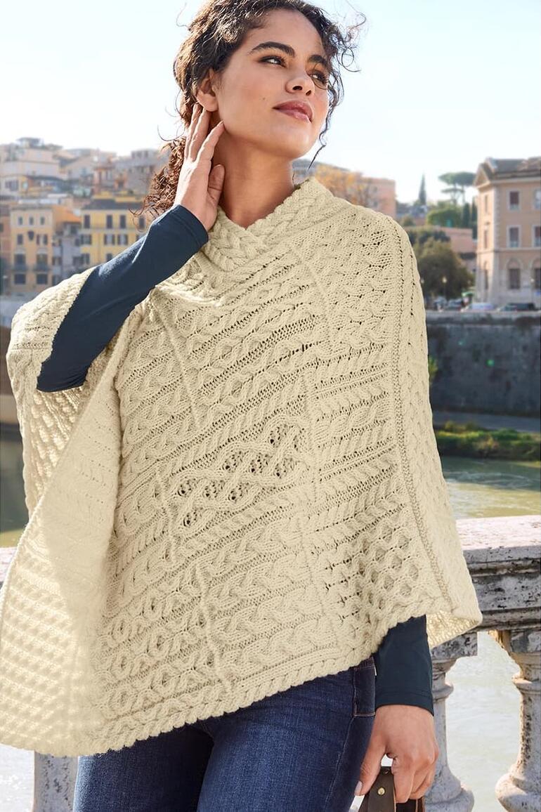 Vrouw in een lichte poncho op een brug met vervaagde jeans.