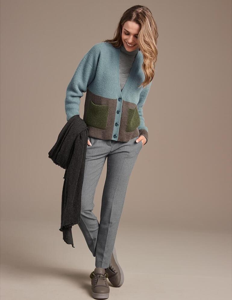 taupe Vrouw in groene cardigan met Chaaya schapenwollen sneakers op een bruine achtergrond.