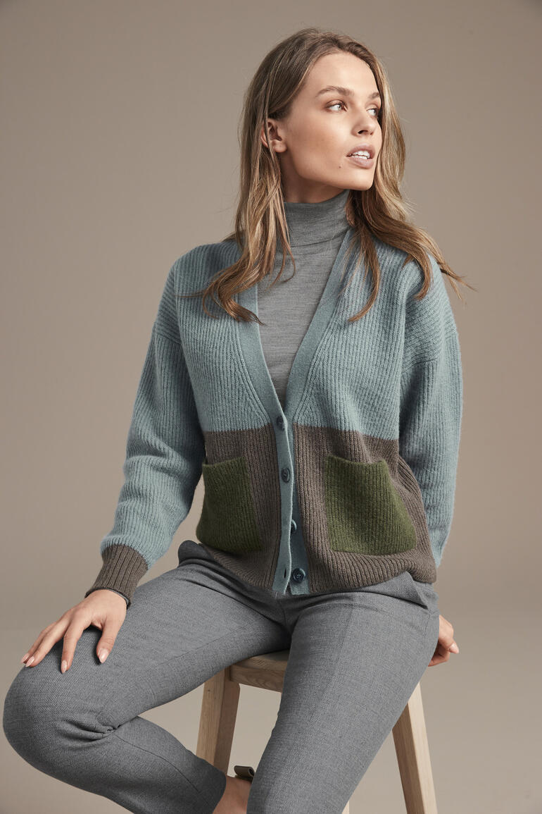 Vrouw draagt een alpaca kleurblok cardigan op een lichte achtergrond.